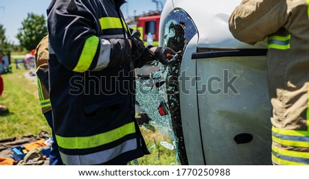 Brave fireman breaking car window and trying to rescue victim of car accident.