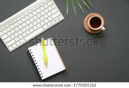 Top view of office desk or flat lay of keyboard, coffee and notepad with pen. Copy space.