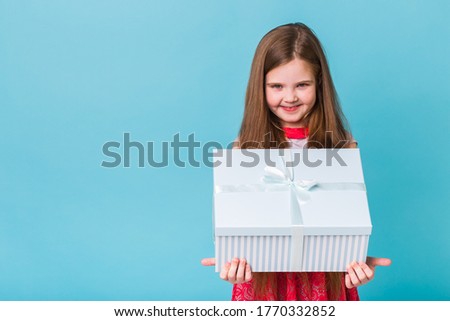 holidays, presents, christmas, childhood and birthday concept - smiling little girl with gift box over blue background