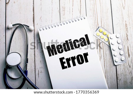 MEDICAL ERROR written on a light wooden table near a stethoscope and pills. Medical concept