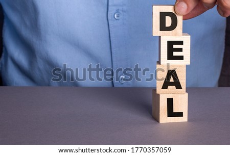 DEAL written on wooden blocks that a man puts on each other