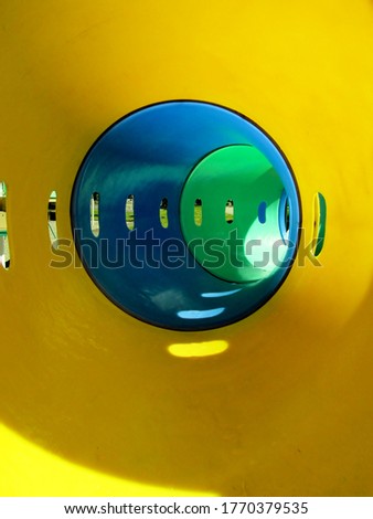 Plastic yellow, blue and green tunnel tube slide at playground