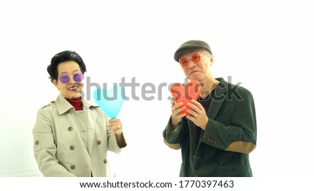 Happy Asian senior elder couple in winter fashion exchange and play heart balloons