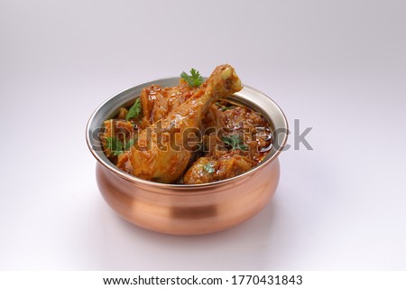 Chicken curry or masala , spicy reddish chicken leg piece dish garnished with coriander leaf ,which is traditionally arranged in a brass bowl  with white background Royalty-Free Stock Photo #1770431843