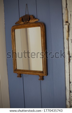 A vintage mirror hanging on blue wood wall