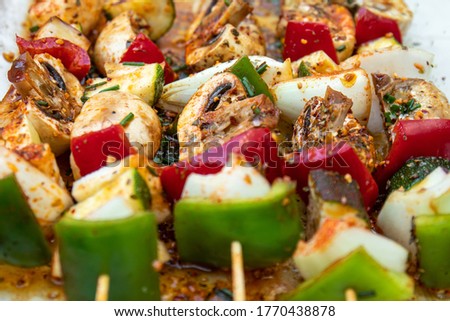 Vegan barbecue skewer. Vegetarian party food with very spiced eggplant, onion and pepper mushrooms. Focus on one point and the rest blurred
