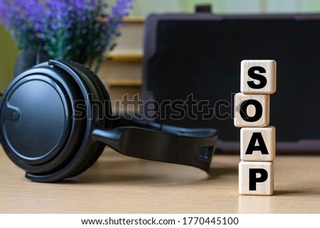 SOAP -word on cubes on the background of the tablet, headphones and a white cup. Technology and computers concept.