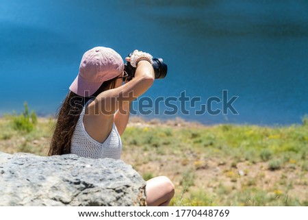 young girl taking professional photos at the edge of a lake on summer vacation