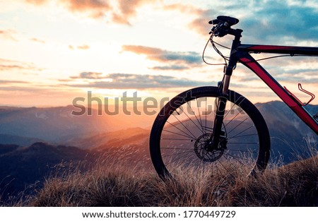 Bicycle wheel on mountain with sunset in background