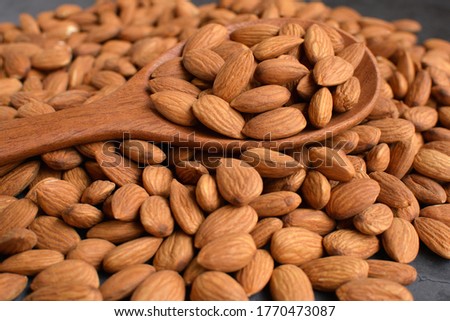 A close-up picture of dried almonds  And a wooden spoon to scoop the beans