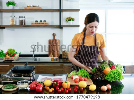 Asian women present fresh food. Shot housewife preparing to cook and showing vegetable in kitchen in house to take picture for sell food box online. Work from home / Stay at home / covid19 concept 