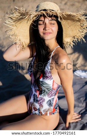 portrait of a dark-haired beautiful girl in a straw hat on the beach
