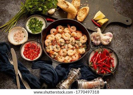 Tasty shrimp tails fried in butter with, garlic, parsley, white wine and chili. With various ingredients on sides. Home seafood concept. Top view, flat lay.