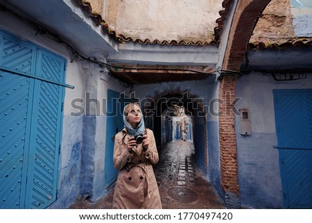 Traveling by Morocco. Young woman walking in medina of blue city Chefchaouen.