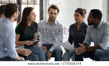 Young professionals company employees diverse staff members gather together sit on chairs brainstorming solving working moments having dispute express opinion point of view. Teamwork briefing activity Royalty-Free Stock Photo #1770506714
