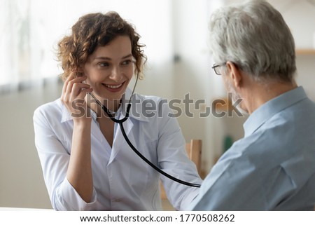 Smiling young female nurse listen to heart rate do regular checkup of mature male patient, positive woman doctor use stethoscope phonendoscope examine senior man client, elderly healthcare concept