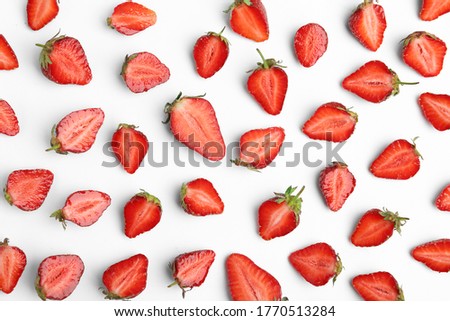 Halves of delicious ripe strawberries on white background, flat lay