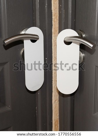 Sign on two white door hanger handle with empty plate do not disturb