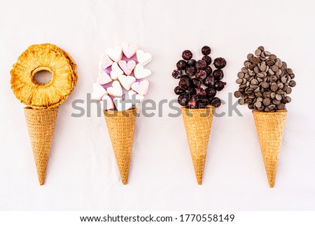 Cones of ice cream with fruits and candy on a white background