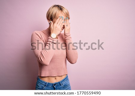 Young blonde woman with short hair wearing casual turtleneck sweater over pink background rubbing eyes for fatigue and headache, sleepy and tired expression. Vision problem