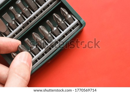 Close up photo of hand pick a Drill bit on red background