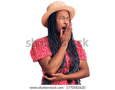 Young african american woman wearing summer hat bored yawning tired covering mouth with hand. restless and sleepiness. 