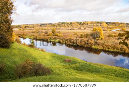 Picturesque autumn landscape with trees, river and sky