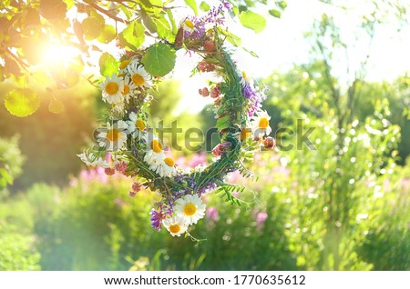 wreath of Meadow flower in summer garden, natural sunny background. Floral crown, symbol of Summer Solstice Day, Midsummer holiday. witch tradition, wiccan ritual. Litha sabbat. template for design Royalty-Free Stock Photo #1770635612