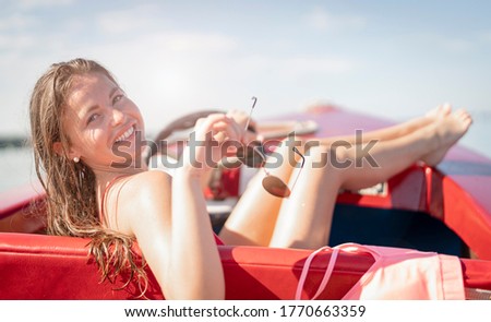 young woman drives a rental boat over the Chiemsee on a beautiful sunny day and sunbathes