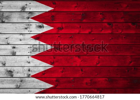 The national flag of Bahrain is painted on a camp of even boards nailed with a nail. The symbol of the country.