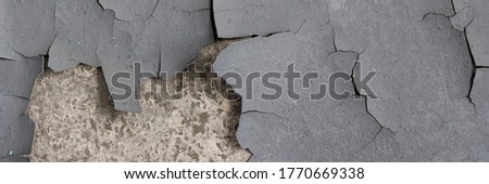 Peeling paint on the wall. Panorama of a concrete wall with old cracked flaking paint. Weathered rough painted surface with patterns of cracks and peeling. Panoramic texture for background and design. Royalty-Free Stock Photo #1770669338