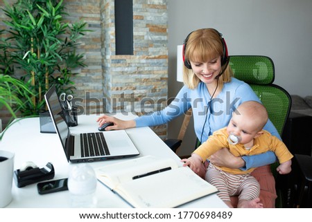 Young mother sitting and holding her child while working