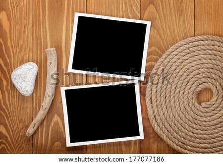 Blank photo frames with ship rope over wooden background