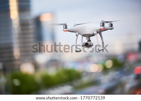 drone with digital camera flying at city street