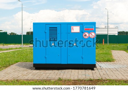 Outdoor emergency power generator with blue housing and special signs.