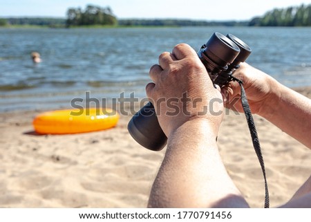 Holding binoculars, photo shot On the beach