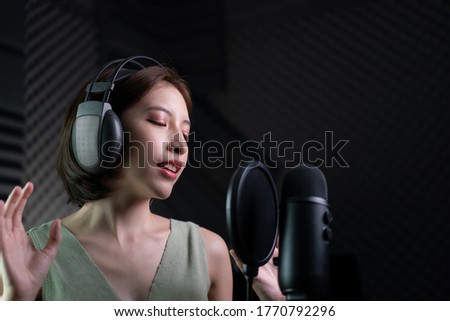 Woman recording a song or storytelling in the studio.