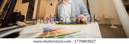 Photographer-designer works at a table, holds a stylus of a graphic tablet in the river