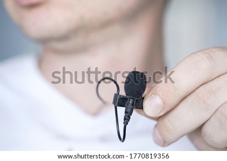 guy holds lavalier microphone in his hand