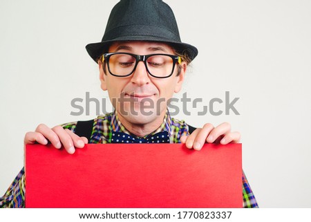 Happy man holding red placard, advertising banner. Space for your text or product. Advertising concept. Seasons sales. Funny nerd showing your product.