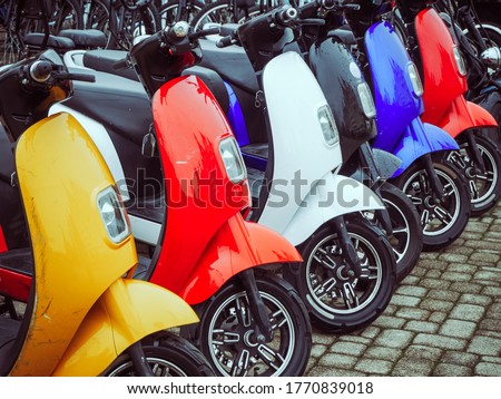 Multicolored electric mopeds stand in a row on paving stones Royalty-Free Stock Photo #1770839018