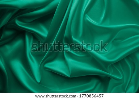 Beautiful smooth elegant wavy emerald green satin silk luxury cloth fabric texture, abstract background design. Card or banner.
