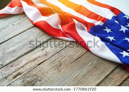 American USA flag freely lying on the textured wooden background. News template about the America. Copy space.