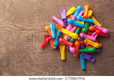 Pile of not inflated balloons different colors on the wood background.