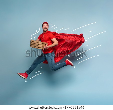 Deliveryman with pizzas acts like a powerful superhero. Concept of success and guarantee on shipment. Studio cyan background Royalty-Free Stock Photo #1770881546