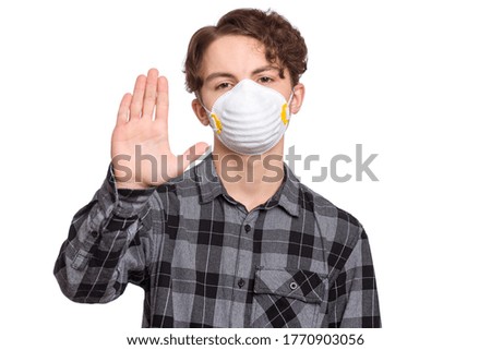 Concept of coronavirus quarantine. Child wearing medical protective face mask during flu virus, making stop gesture. COVID-19 - home self isolation. Teen Boy doing stop sign, isolated on white.