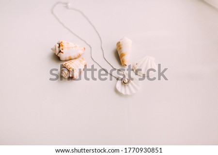 On a white table.  Shell and pearl necklace.  Bright and girly feeling.  Cute and lovely vintage silver accessories.