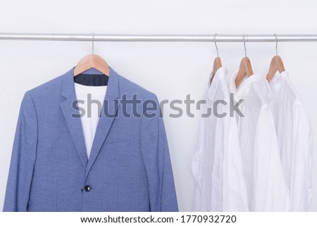 Blue suit with white shirt blue long sleeved shirts on hanger
