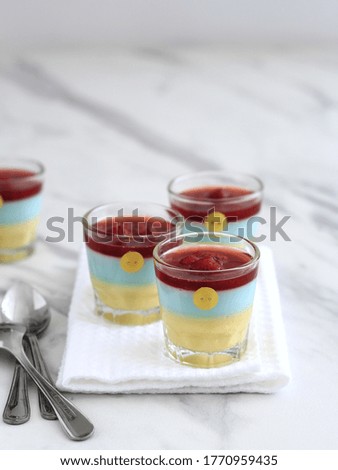rainbow silky pudding with strawberry jam topping on glass. Selective focus