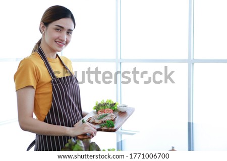 Asian women present fresh food. Shot housewife showing pork or meat steak and vegetable in kitchen in house to take picture for sell food box online. Work from home / Stay at home / covid19 concept 